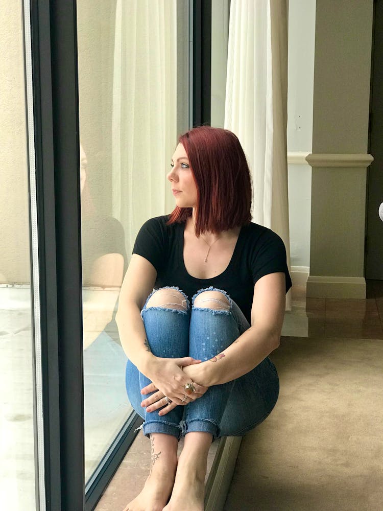 Girl sat on the floor looking out a window Girl sat on the floor looking out a window